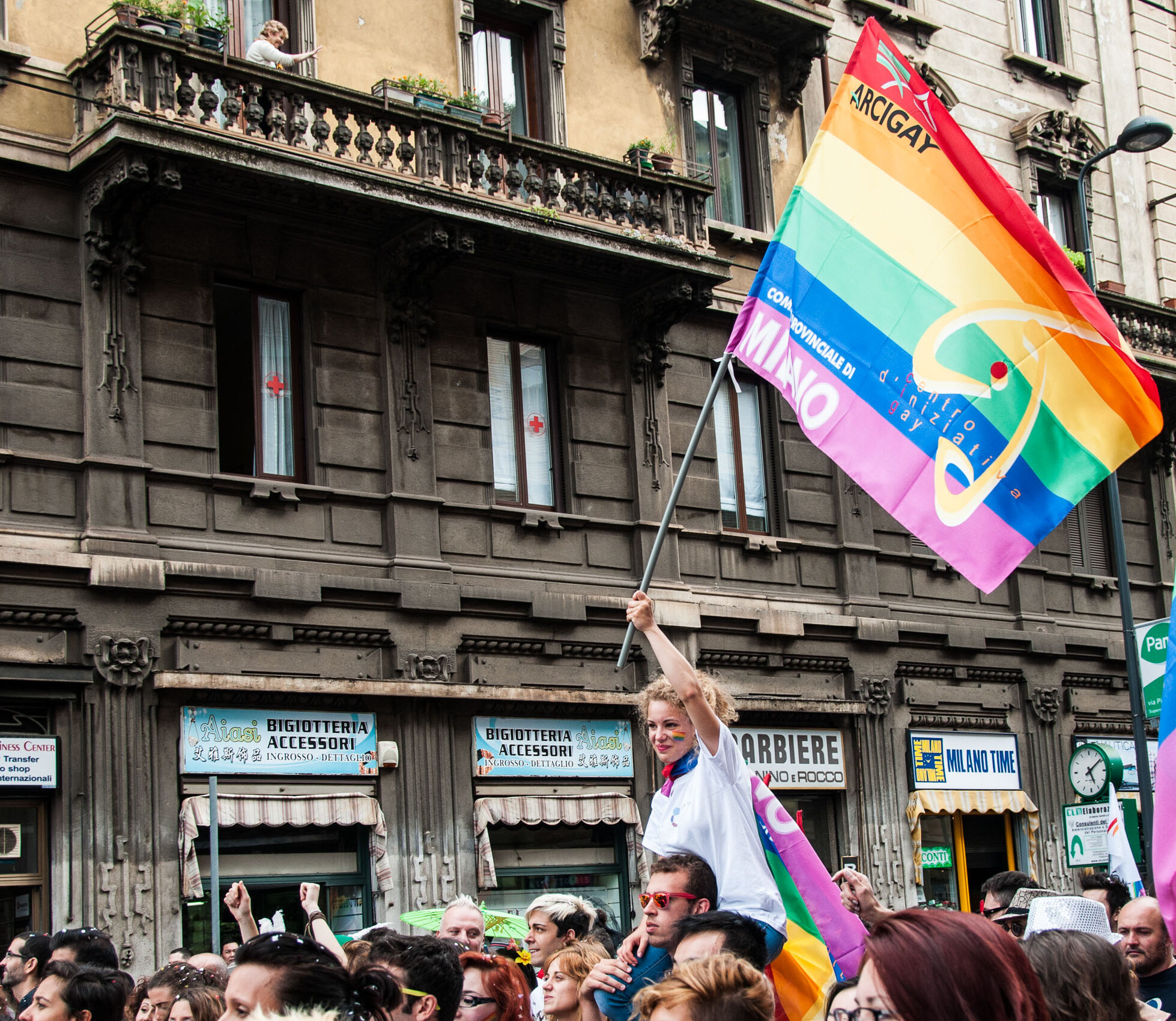 Una ragazza sventola la bandiera arcobaleno del CIG durante il Milano Pride